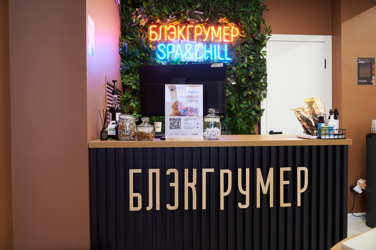 Стойка администратора в салоне «Блэкгрумер» с неоновой вывеской сети